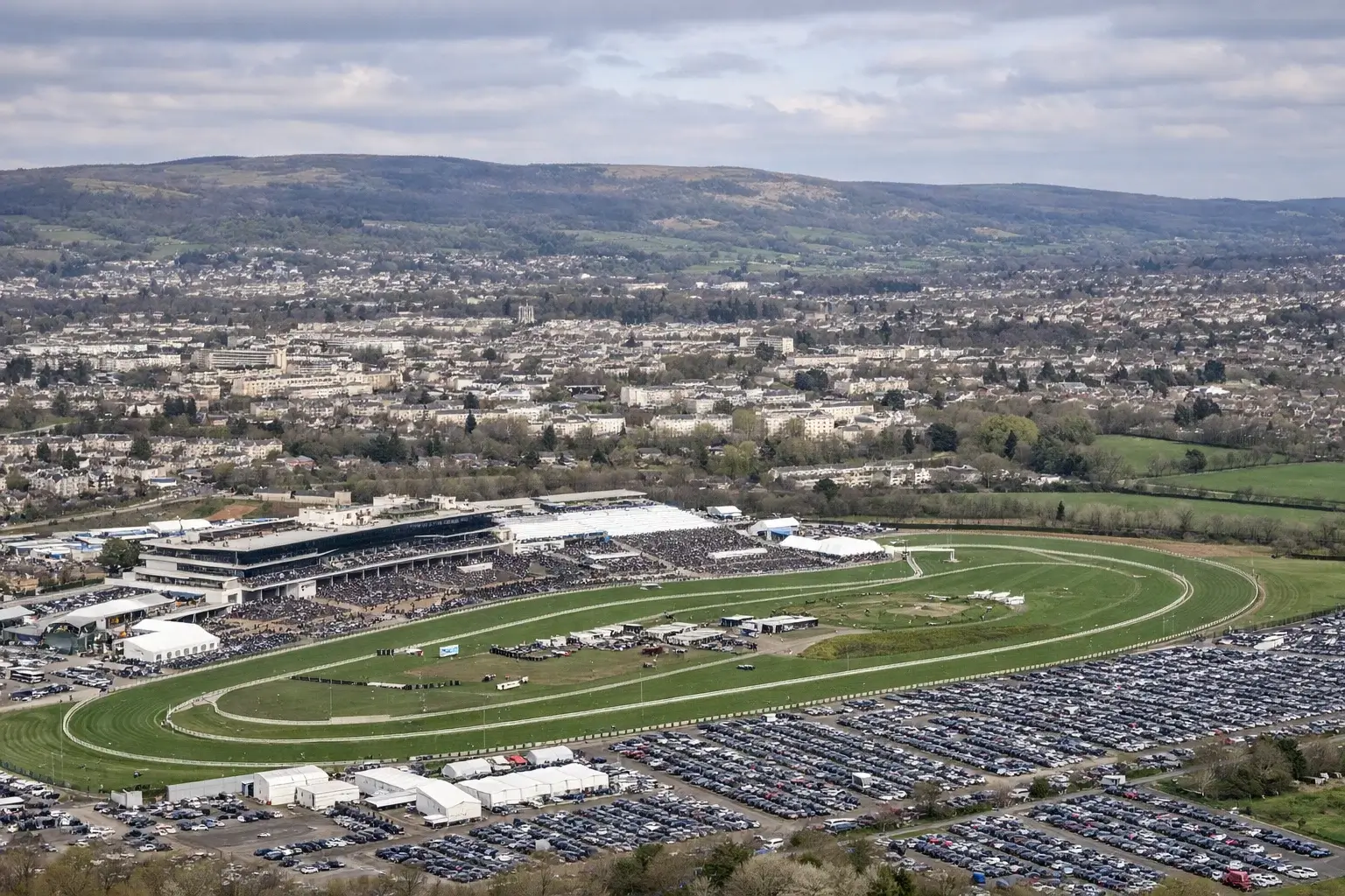 Aerial view of Cheltenham town and racecourse during festival week showing crowds and surrounding area